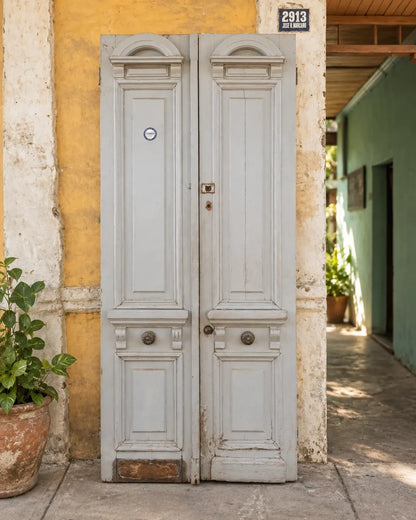 Par de puertas antiguas altas de madera con molduras y herrajes originales